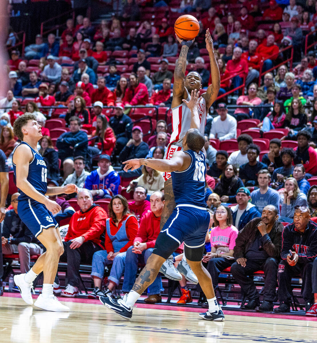 UNLV guard Luis Rodriguez (15) gets off a three-point basket attempt over Utah State Aggies gua ...