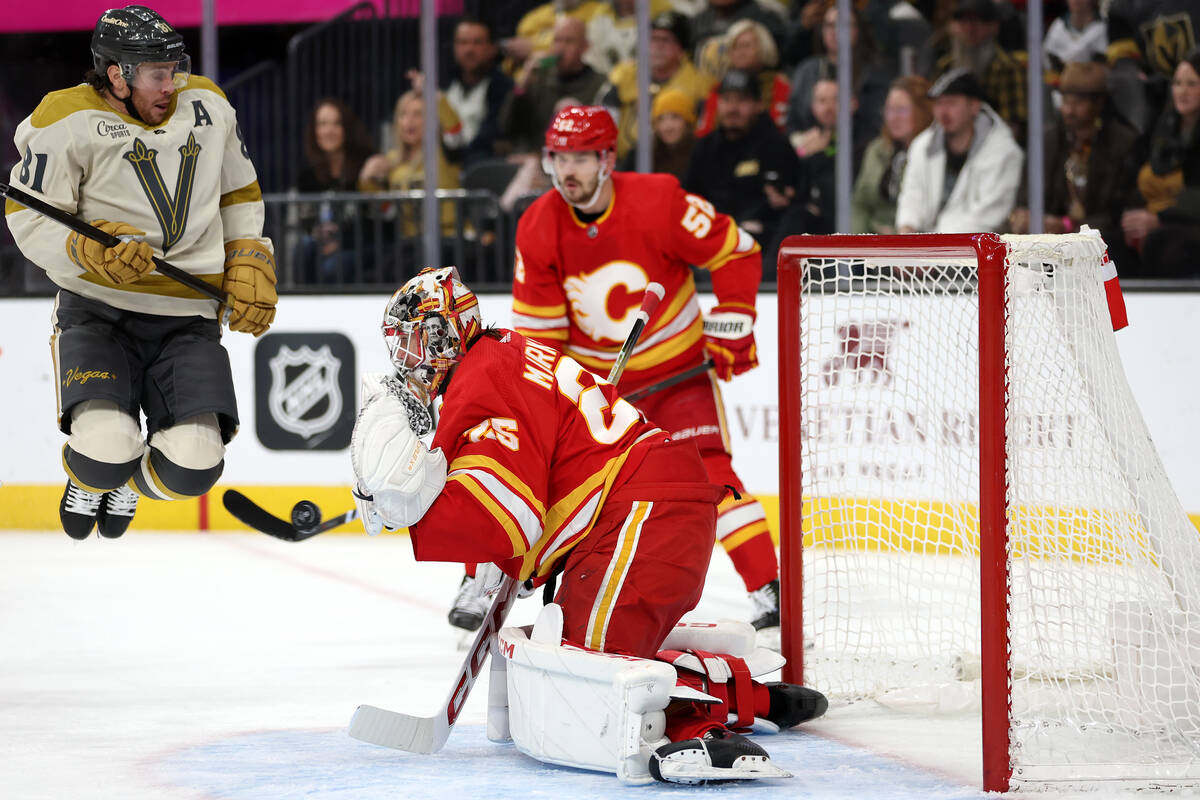 Golden Knights right wing Jonathan Marchessault (81) jumps to avoid the puck while Flames goalt ...