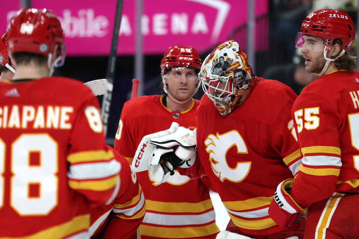 The Flames congratulate goaltender Jacob Markstrom (25) after they won an NHL hockey game again ...