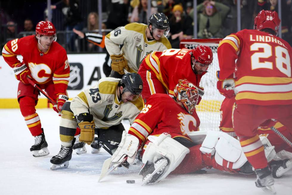 Golden Knights center Paul Cotter (43) battles for the puck with Flames goaltender Jacob Markst ...