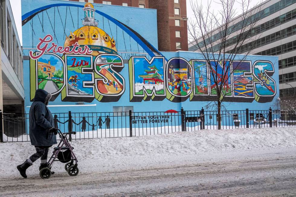 A woman walks past a mural in downtown Des Moines, Iowa, Saturday, Jan. 13, 2024. (AP Photo/And ...