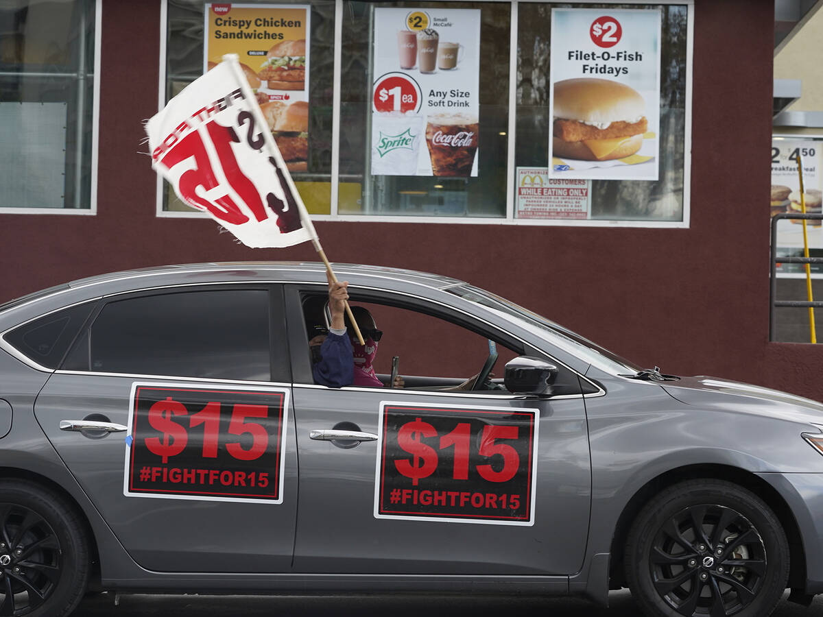 FILE - Fast-food workers drive though a McDonald's restaurant demanding a $15 hourly minimum wa ...