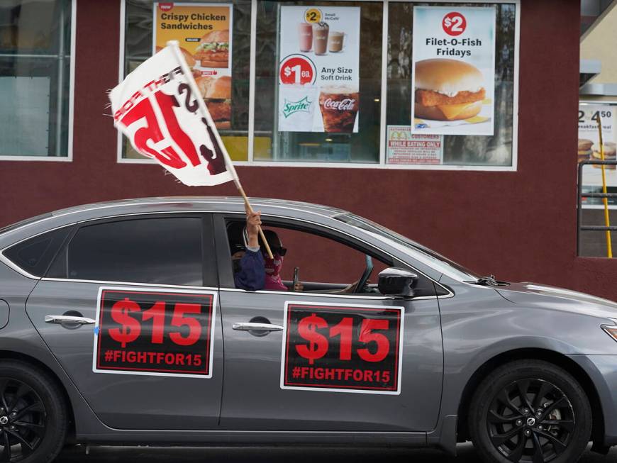 FILE - Fast-food workers drive though a McDonald's restaurant demanding a $15 hourly minimum wa ...