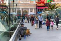 Pedestrians walk along as panhandlers and performers occupy spots along the bridge leading to N ...