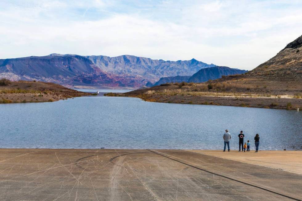 Visitors stand at the shoreline as water is flowing again into Boulder Harbor after being empt ...