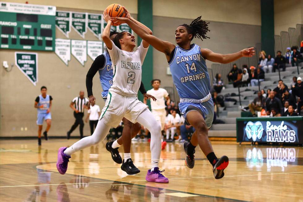 Rancho guard Jakoi Lide (2) drives toward the hoop against Canyon Springs guard Henry King (14) ...