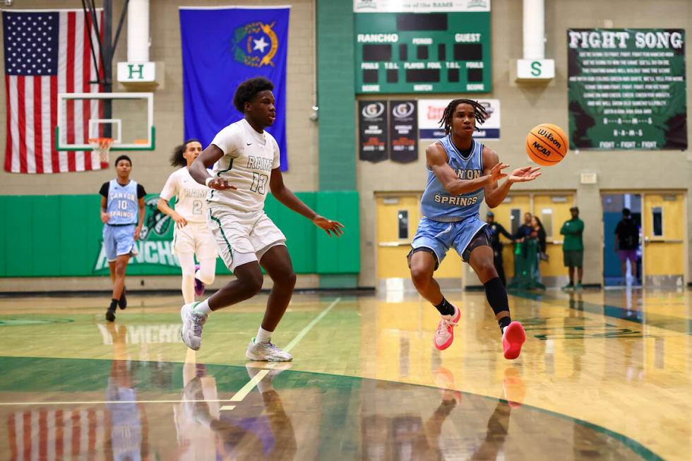 Canyon Springs guard Emanuel Custard passes while Rancho guard Ahmad Koroma (13) catches up to ...