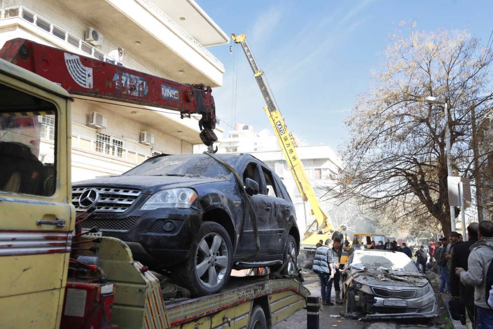 Emergency services work at a building hit by an air strike in Damascus, Syria, Saturday, Jan. 2 ...