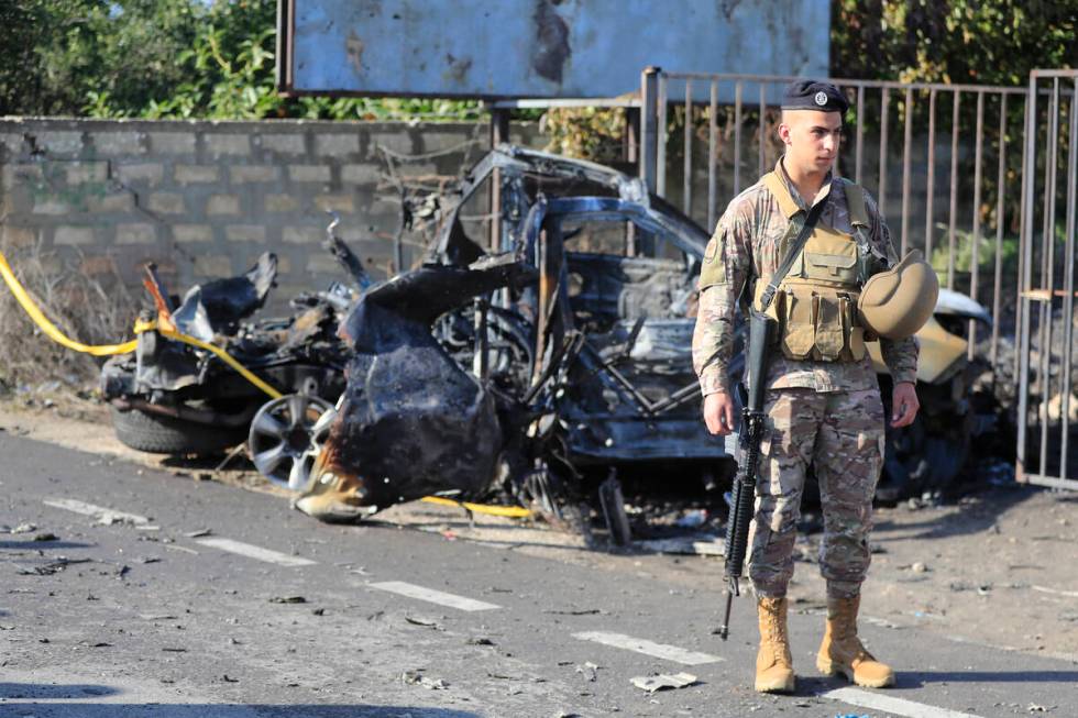 A Lebanese soldier stands next to a damaged car in the southern town of Bazouriyeh, Lebanon, Sa ...