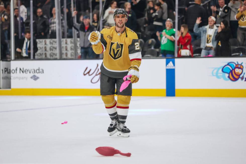 Golden Knights defenseman Alec Martinez (23) picks up plastic flamingo toys off of the ice afte ...