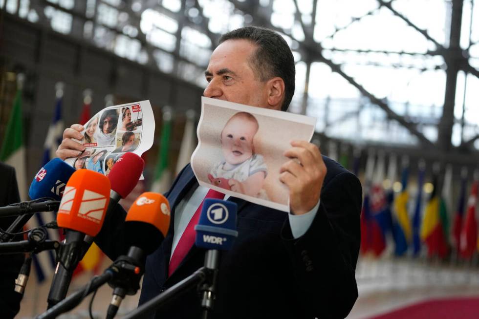 Israel's Foreign Minister Israel Katz holds up a paper photo of hostages kidnapped during the O ...