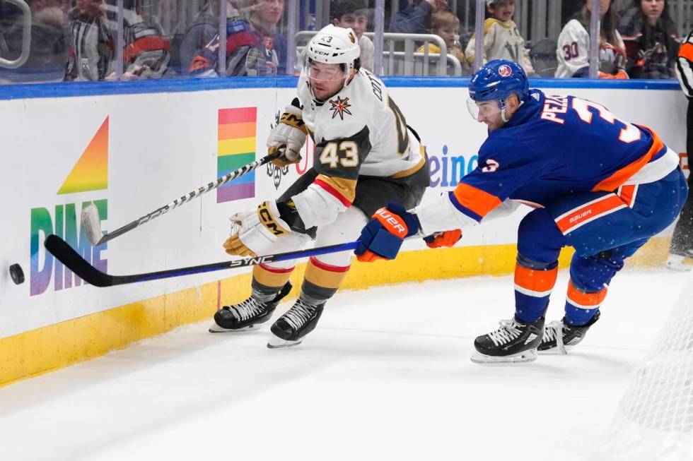 New York Islanders' Adam Pelech (3) and Vegas Golden Knights' Paul Cotter (43) reach for the pu ...