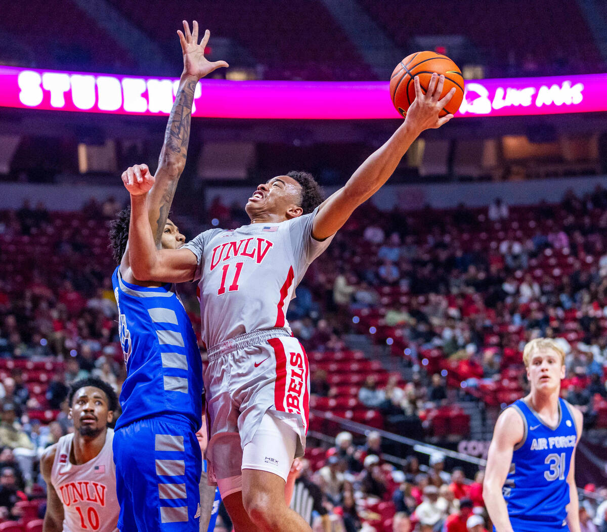 UNLV guard Dedan Thomas Jr. (11) scores past Air Force Falcons forward Chase Beasley (13) durin ...