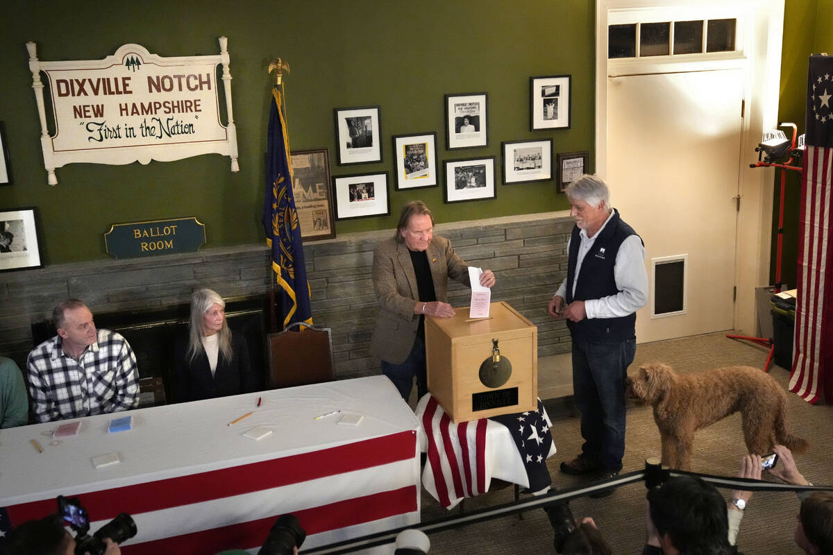 Les Otten, far right, has his vote inserted into the ballot box by town moderator Tom Tillotson ...