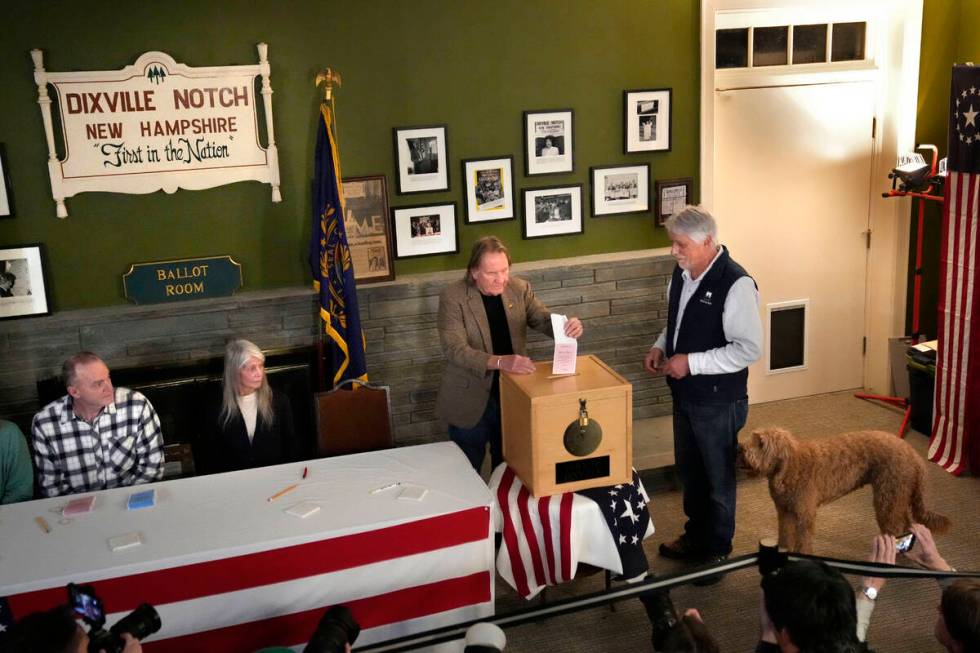 Les Otten, far right, has his vote inserted into the ballot box by town moderator Tom Tillotson ...