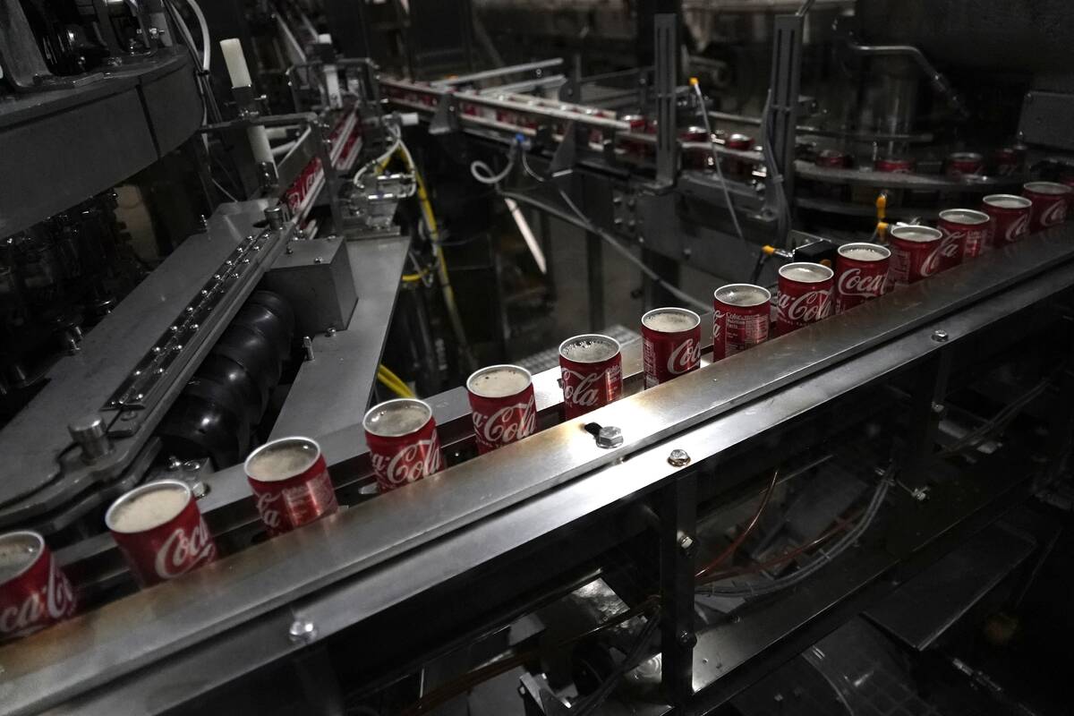 File - Coca-Cola cans move down a conveyer belt in the Swire Coca-Cola bottling plant on Oct. 2 ...