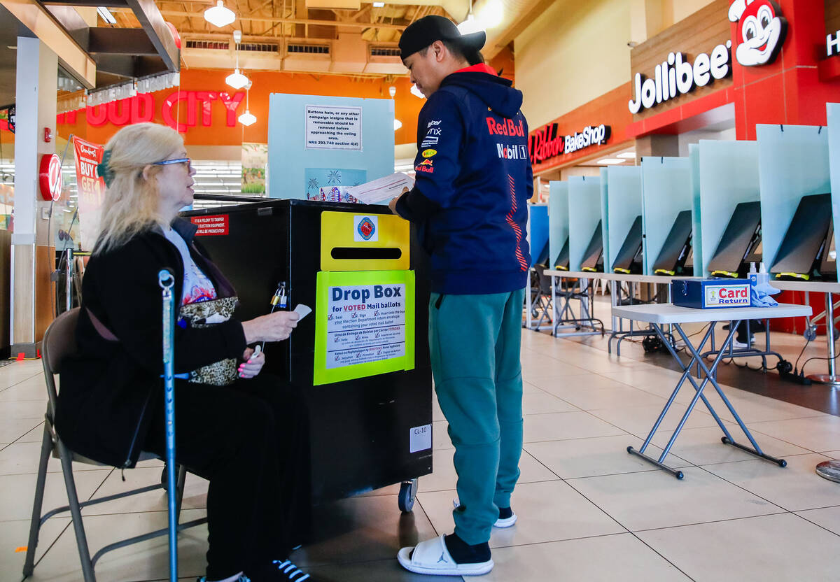 Dallas-Lee Brower, a poll worker, helps Raymond Valdez drop off his ballot during early voting ...