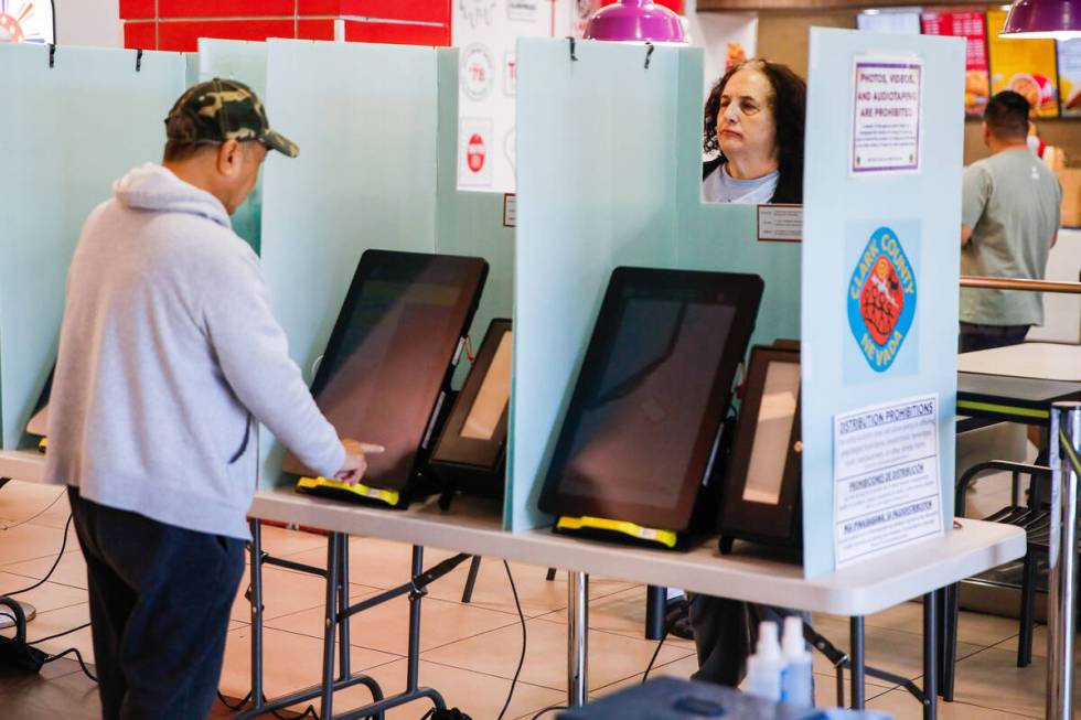 Joan Gaiptman, right, a poll worker, helps out a voter during the early voting period at Seafoo ...