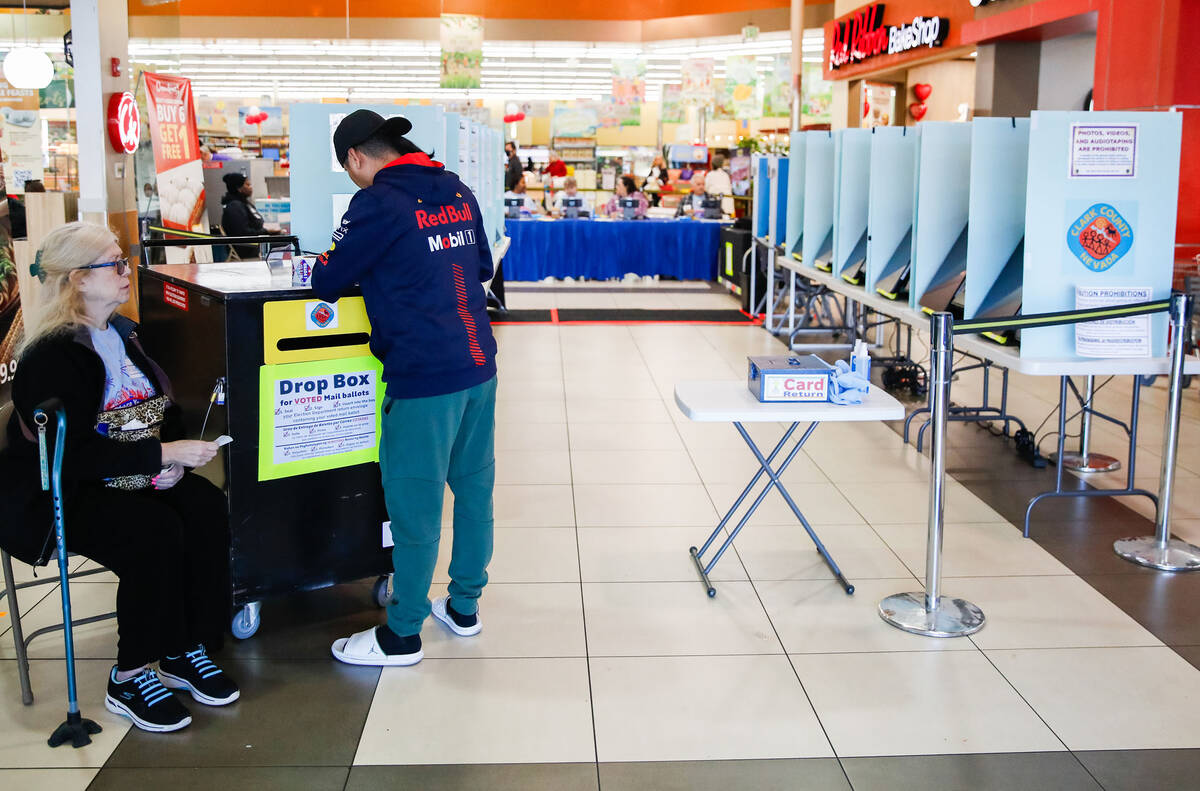 Dallas-Lee Brower, a poll worker, helps Raymond Valdez drop off his ballot during early voting ...