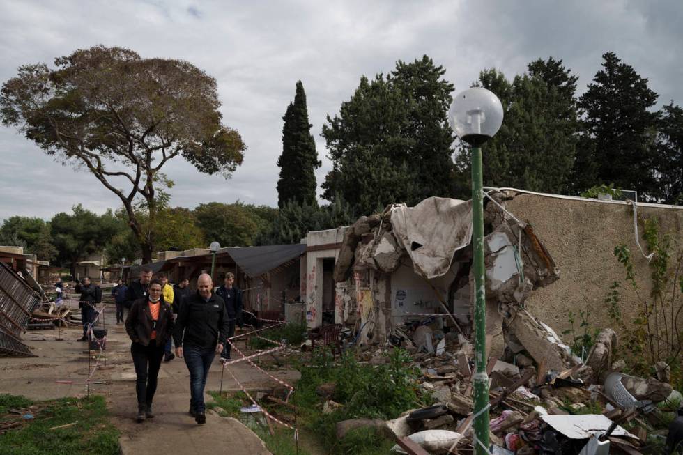 People walk past houses destroyed during the cross-border attack by Hamas on Oct. 7, as they vi ...