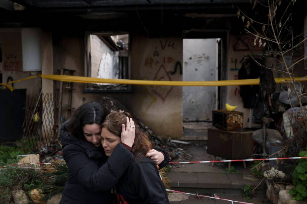 Amit Soussana, 40, right, is embraced by a friend after speaking to journalists in front of her ...