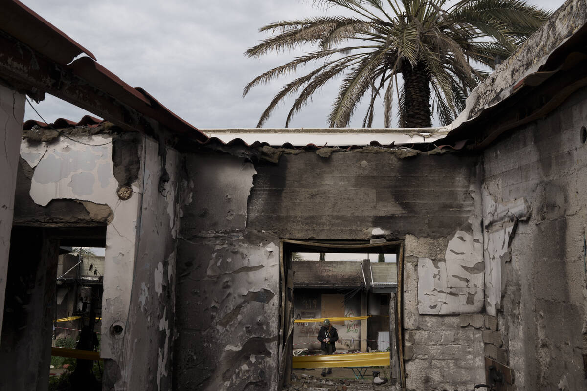 A woman walks past a destroyed house in the kibbutz Kfar Azza, near the Gaza Strip, Israel, Mon ...