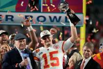 Kansas City Chiefs quarterback Patrick Mahomes (15) holds the Vince Lombardi Trophy next to Ter ...