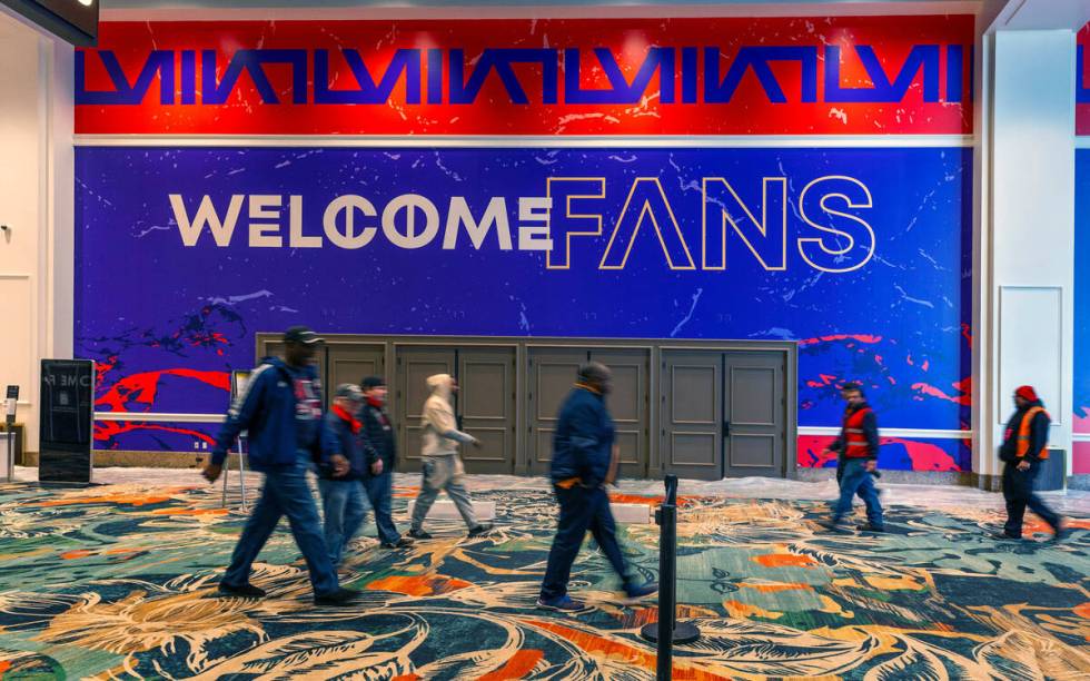 People walk by a large welcome sign in the hallway as set up continues inside for the Super Bow ...