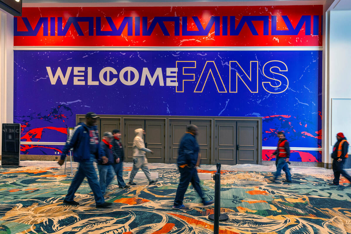 People walk by a large welcome sign in the hallway as set up continues inside for the Super Bow ...