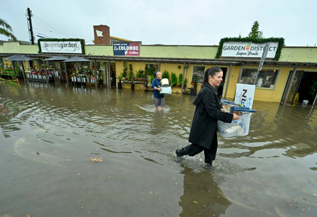 Mandy Garrett and Joe Garnett remove items from the flooded Devynn's Garden on Marina Drive, ju ...