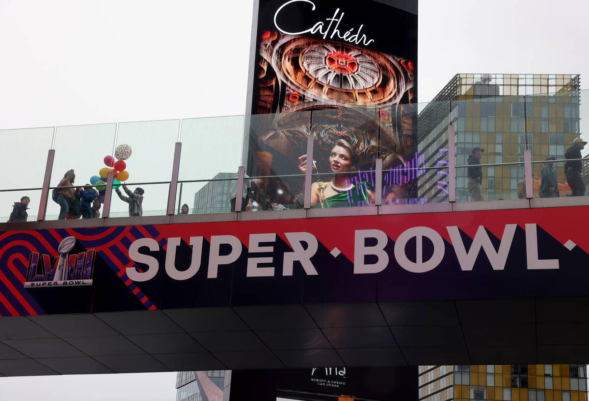 People walk past Super Bowl signage on the Strip at Harmon Avenue in Las Vegas on Thursday, Feb ...