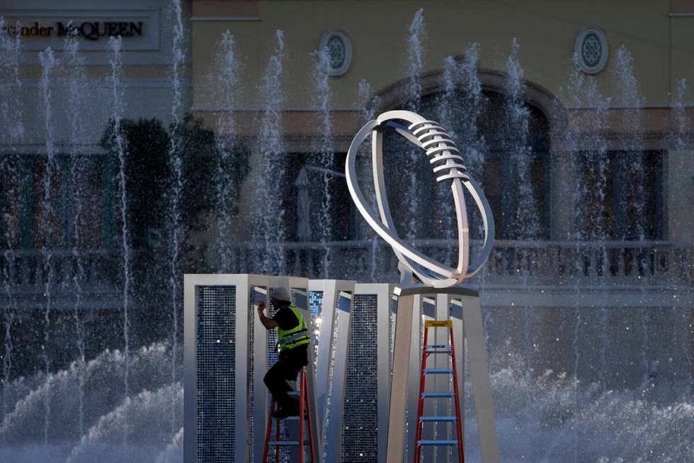 A worker erects a Lombardi Trophy statue at the Bellagio fountains ahead of the Super Bowl 58 f ...