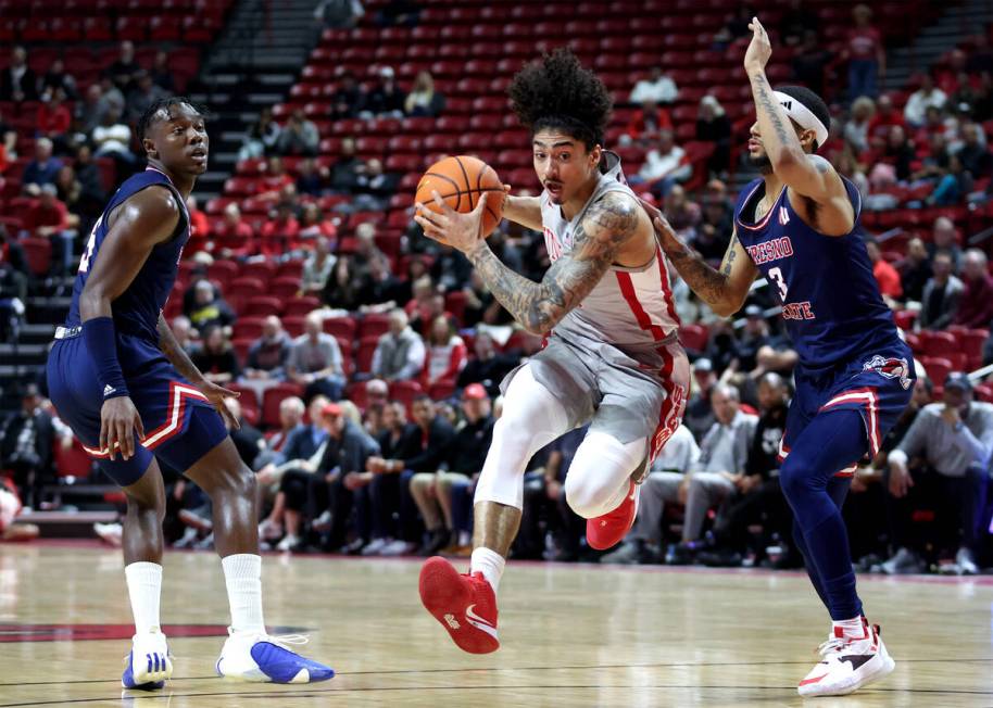 UNLV Rebels guard Brooklyn Hicks (13) dribbles through defense by Fresno State Bulldogs guard J ...