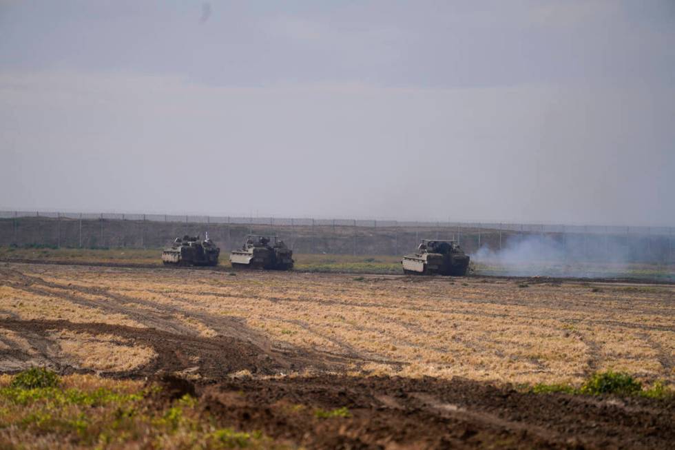 Israeli soldiers drive in their armored vehicles in southern Israel near the border with the Ga ...