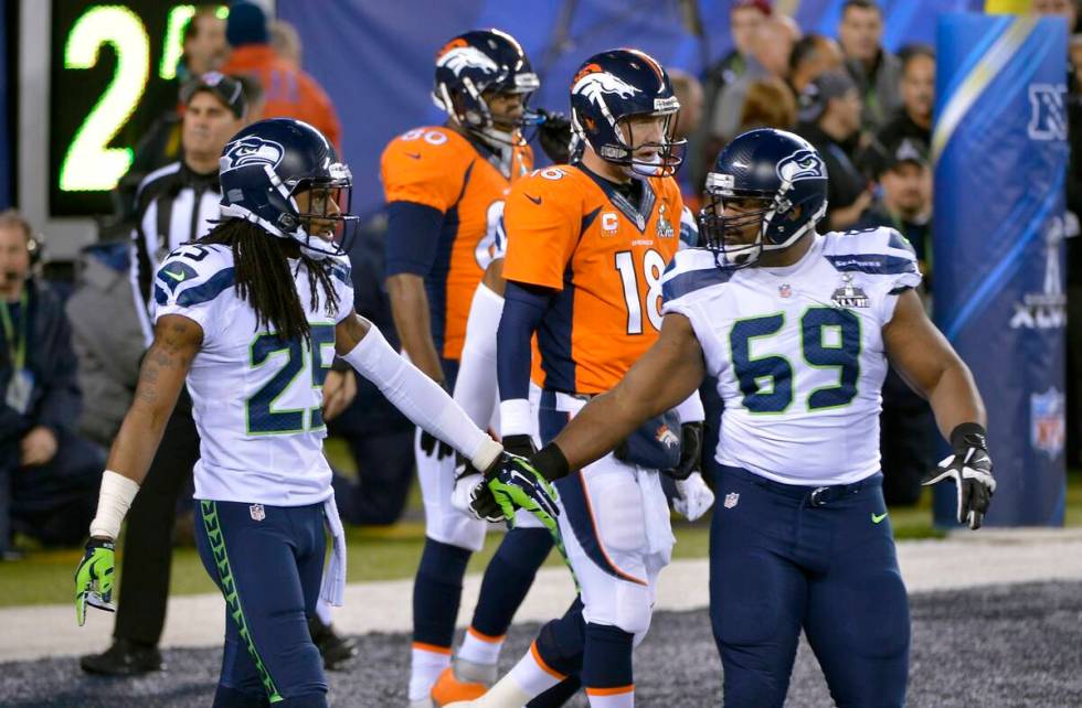 Seattle Seahawks' Richard Sherman, left, and Clinton McDonald, right, react in front of Denver ...