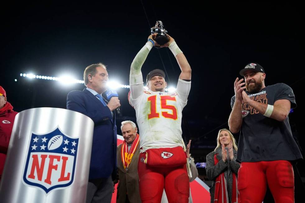 Kansas City Chiefs quarterback Patrick Mahomes (15) holds up the Lamar Hunt Trophy next to Kans ...