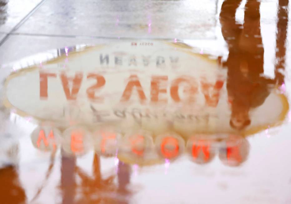 A pedestrian and the “Welcome to Fabulous Las Vegas Nevada” sign are reflected in ...