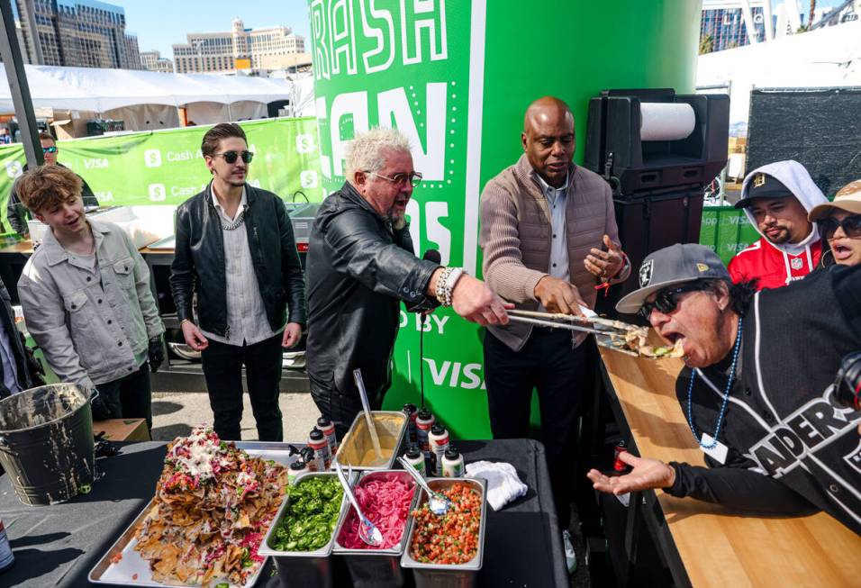 Celebrity chef Guy Fieri feeds a serving of trash can nachos to David Ortiz, from Los Angeles, ...