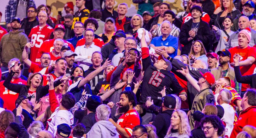 A fan makes a grab for a t-shirt tossed to the crowd during the Super Bowl Opening Night celebr ...