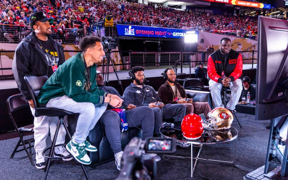 Kansas City Chiefs players and friends play a video game on the field during the Super Bowl Ope ...