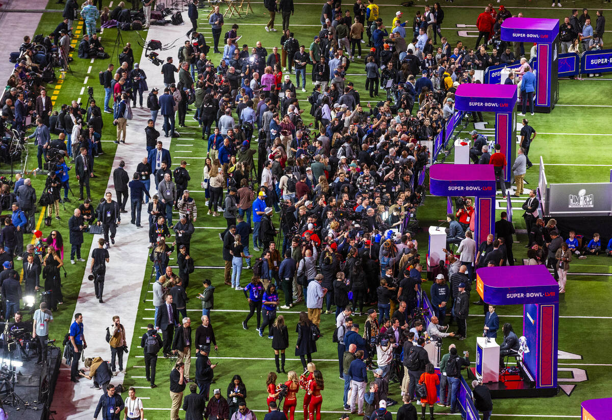 Media members and guests gather on the field as Kansas City Chiefs players and coaches take que ...