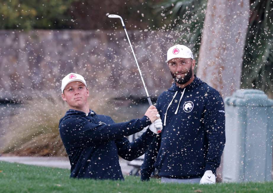 Jon Rahm, right, watches Caleb Surratt's hit during practice before the LIV Golf Las Vegas tour ...