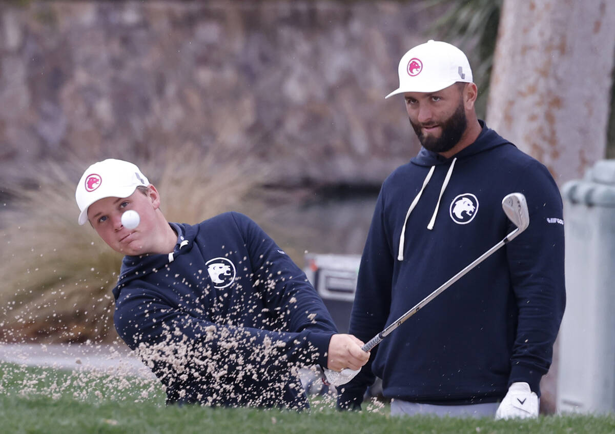 Jon Rahm, right, watches Caleb Surratt's hit during practice before the LIV Golf Las Vegas tour ...