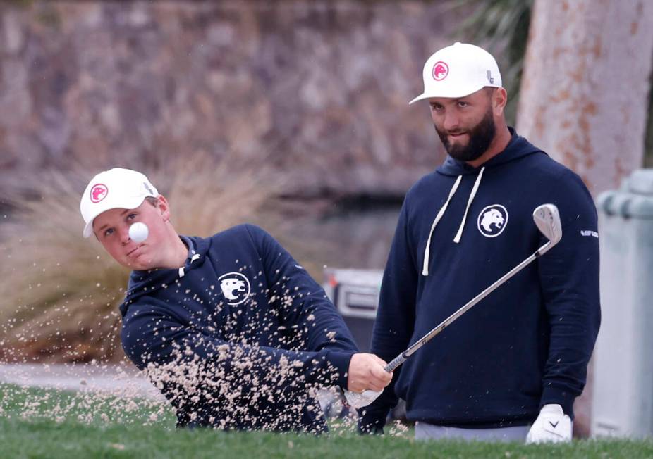 Jon Rahm, right, watches Caleb Surratt's hit during practice before the LIV Golf Las Vegas tour ...