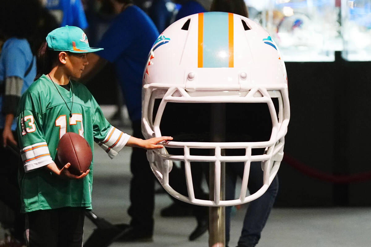 A Miami Dolphins fan touches an oversized Dolphins helmet at the Super Bowl Experience, the ope ...