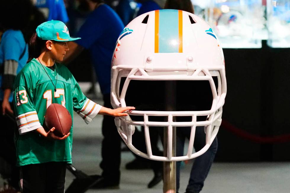 A Miami Dolphins fan touches an oversized Dolphins helmet at the Super Bowl Experience, the ope ...