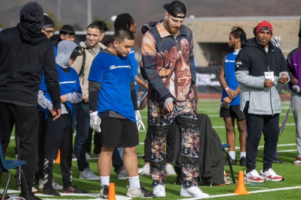Raiders defensive end Maxx Crosby, left, works with a participant of the Field the Future Madde ...