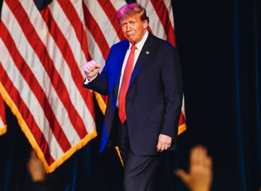 Former President Donald Trump pumps his fist as he enters to speak at a caucus night watch part ...