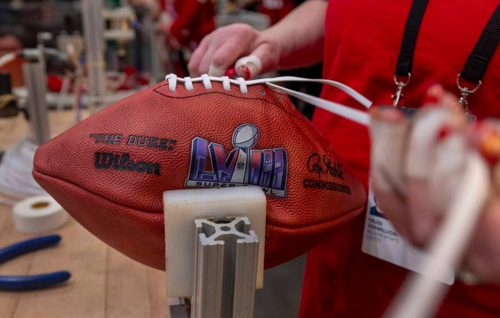 Trudi Vermillion with Wilson hand laces a new football in their football making display space d ...