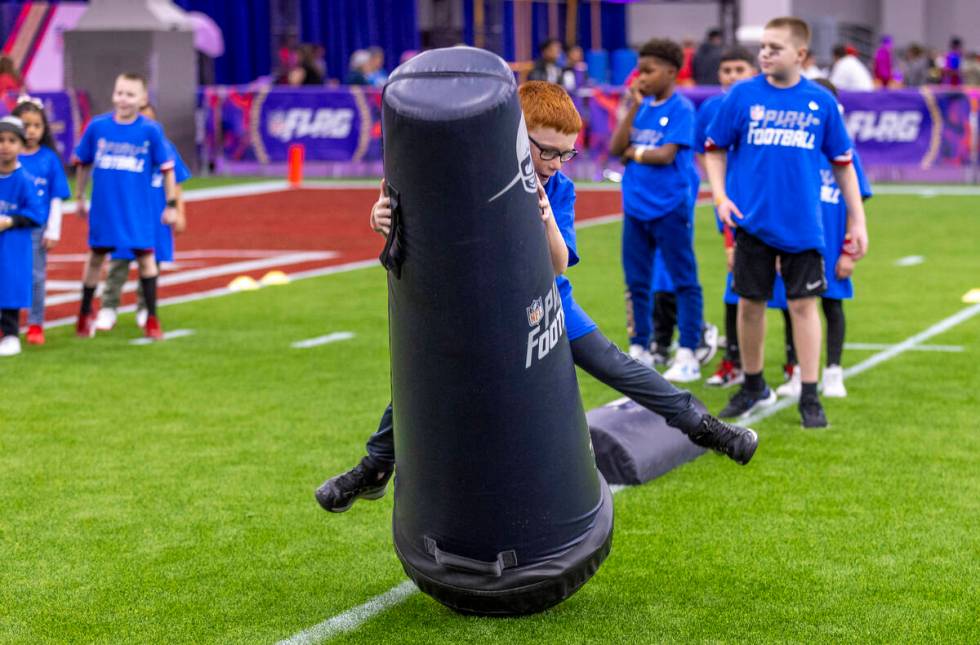 A young fan tackles a dummy during a skills training session at the Super Bowl Experience at th ...